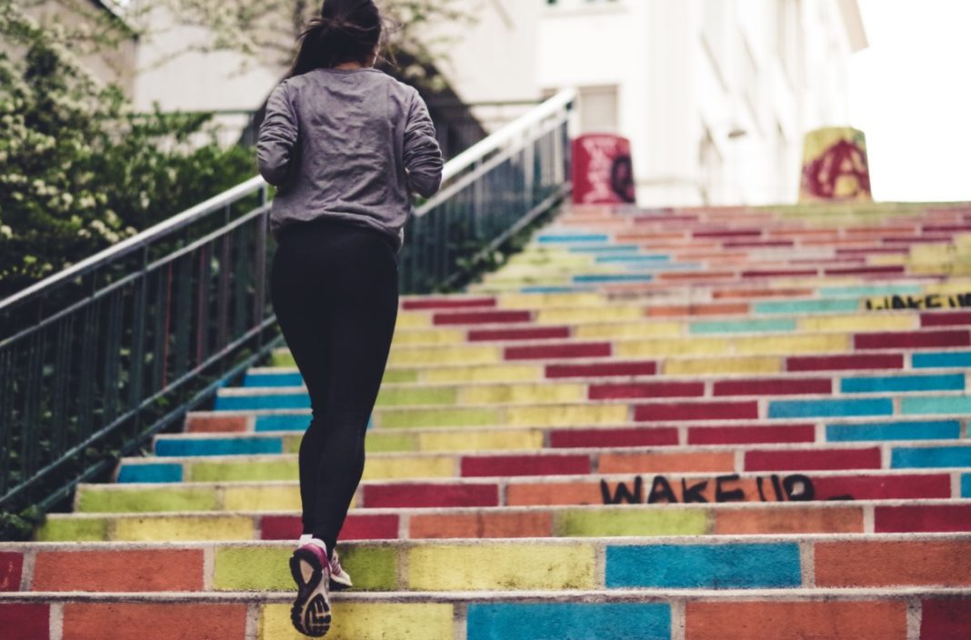 Girl jogging up colourful staircase