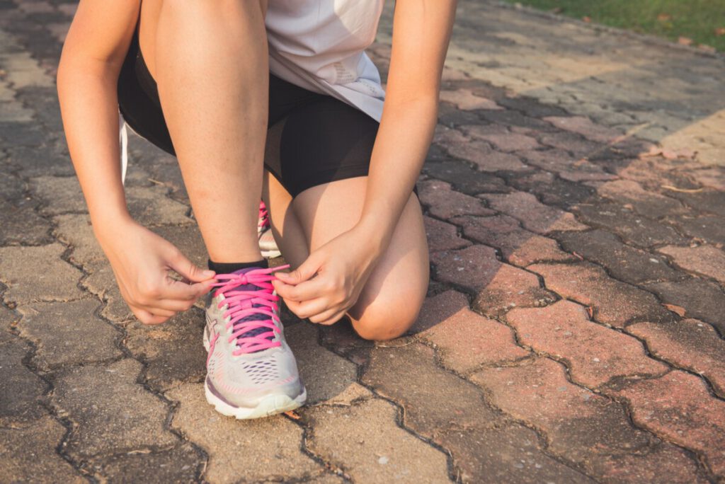 woman-kneeling-to-tie-running-shoe