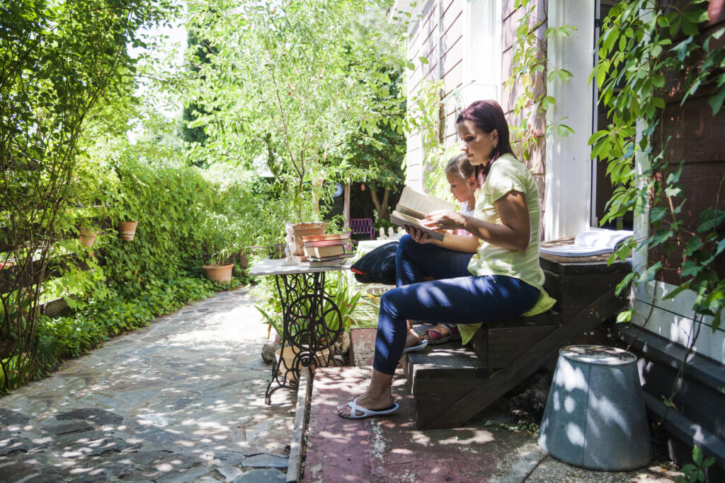 family-on-porch-reading-book-natural-garden-sustainable-