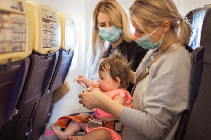 two-women-travelling-with-baby-onboard-plane-wearing-medical-face-masks