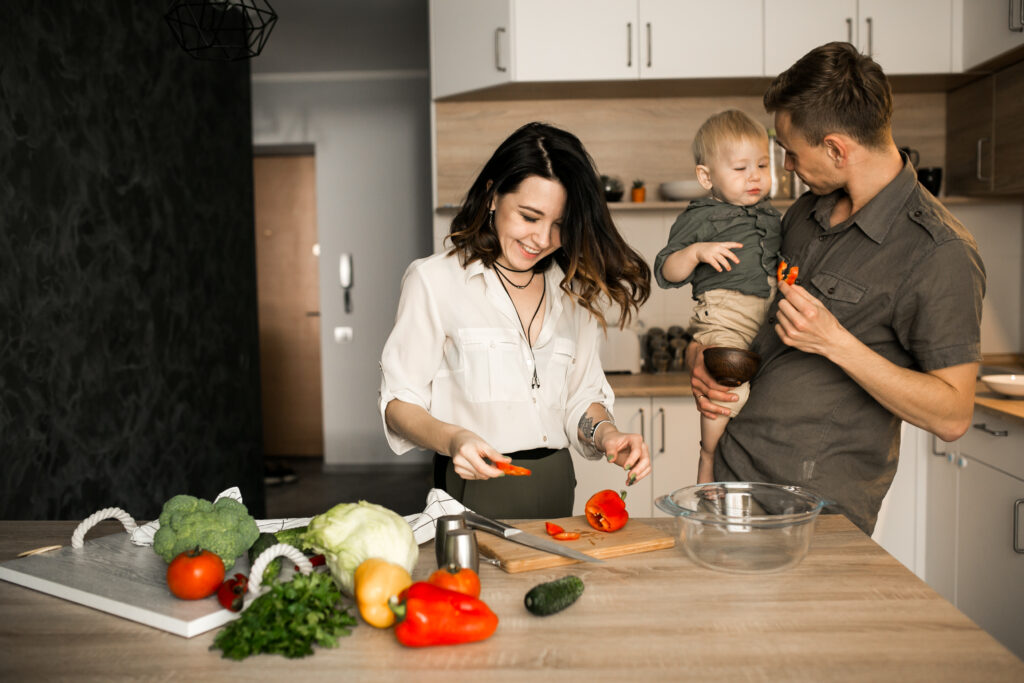  father-holding-his-kid-as-the-mother-chops-vegetables