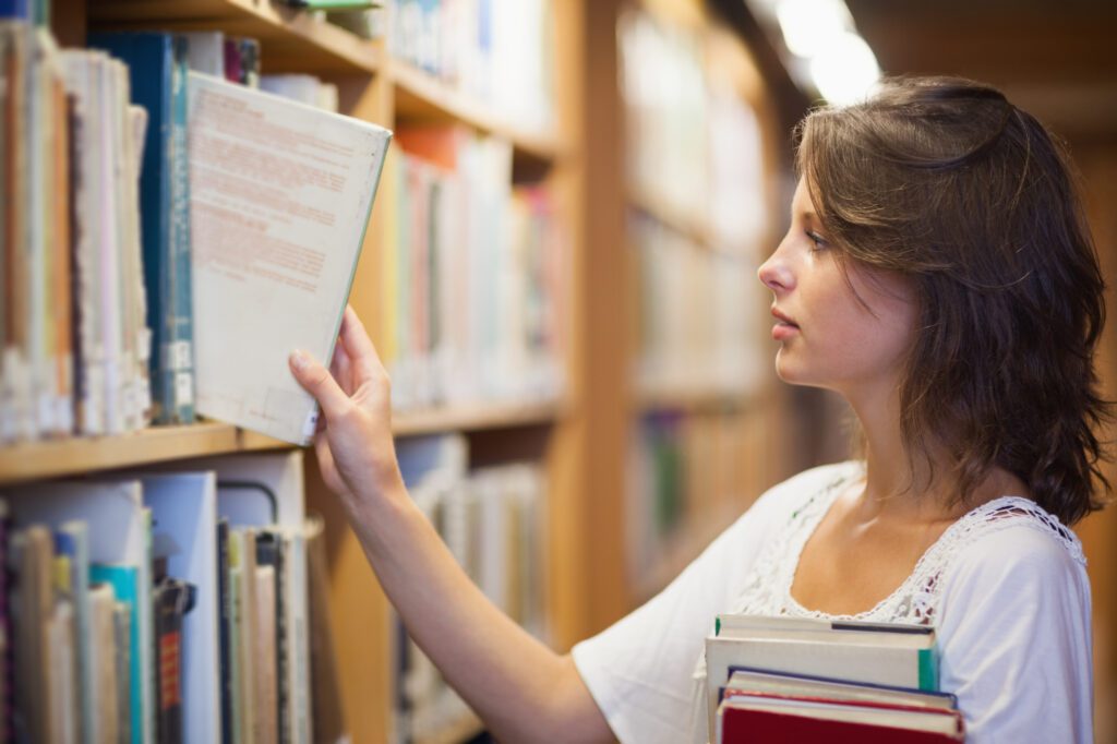 female-international-student-looking-at-books-at-library-of-dutch-international-school