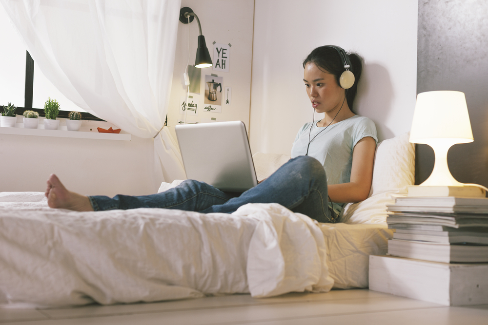 photo-female-student-sitting-in-bed-searching-for-student-housing-in-the-netherlands