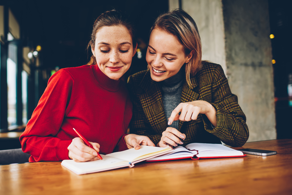 two-women-friends-writing-in-agendas-to-confirm-plans