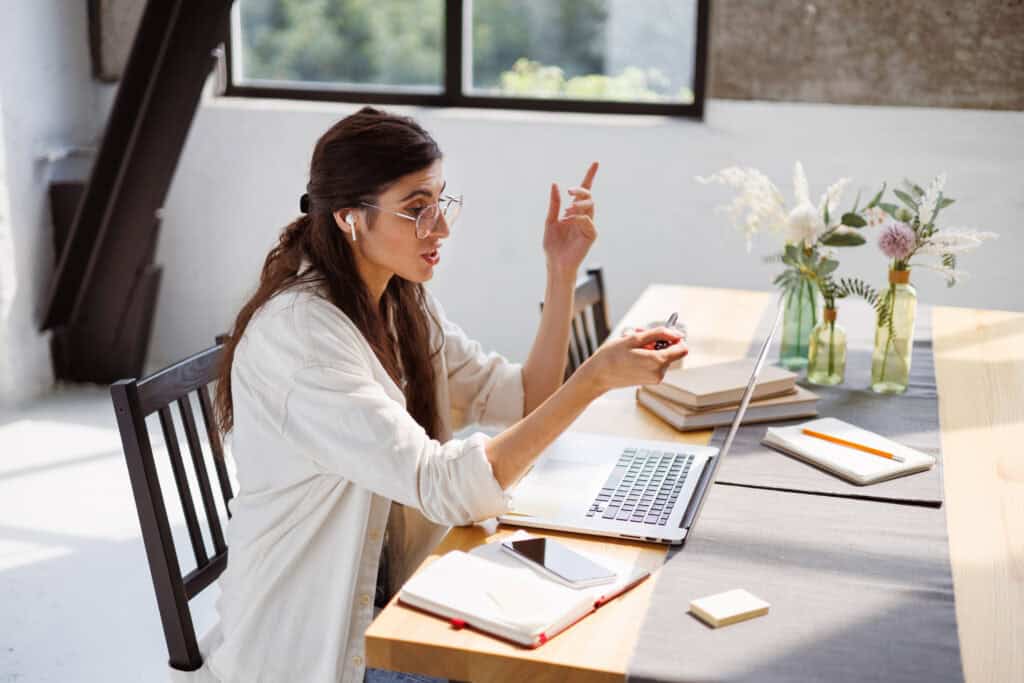 freelancer-earphone-having-video-call-laptop-while-working-near-notebooks-home
