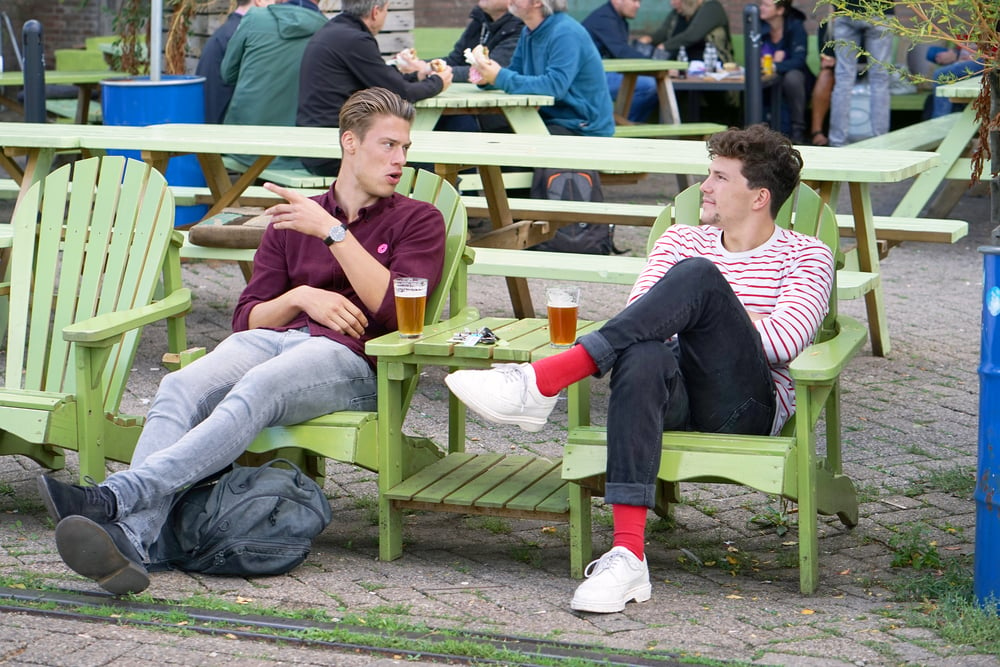 two-friends-drinking-beer-at-terrace-in-rotterdam-talking-dutch