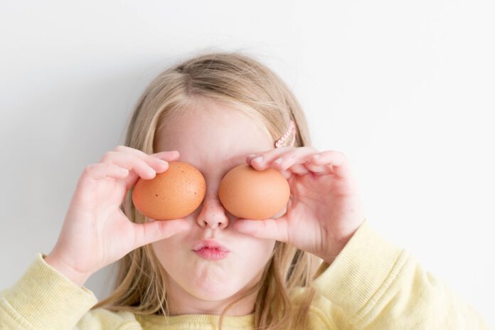 Girl-holding-two-eggs-over-her-eyes-and-makes-a-funny-face