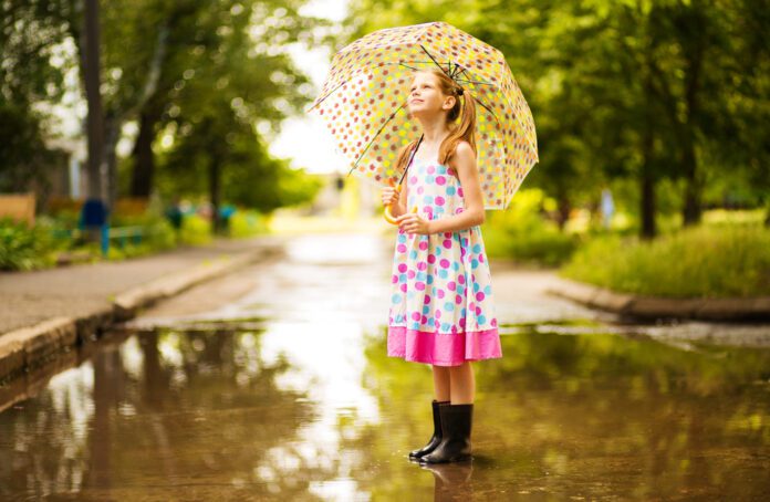 photo-of-young-girl-standing-in-puddle-after-rain-with-umbrella-summer-day