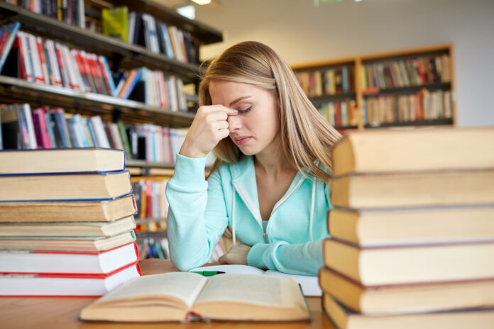 photo-of-girl-surrounded-by-textbooks-tired-and-stressed