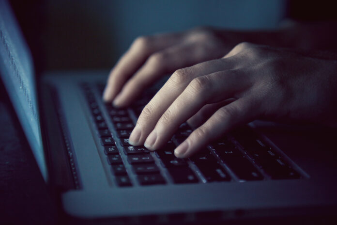hands-typing-on-laptop-dark-room