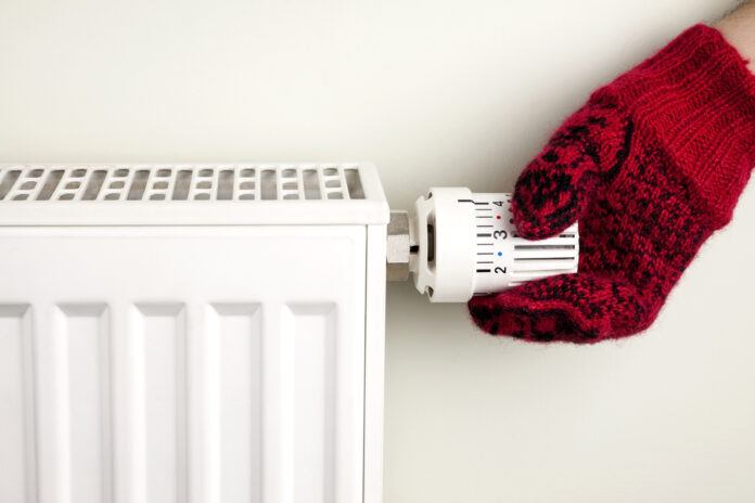 hand-with-mitten-turning-down-heat-to-save-money-on-energy