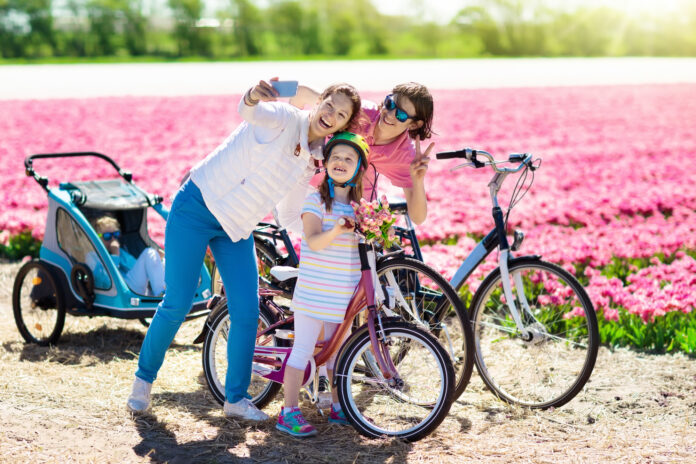 photo-of-happy-dutch-family-in-front-of-pink-tulip-field-taking-selfie-with-bikes