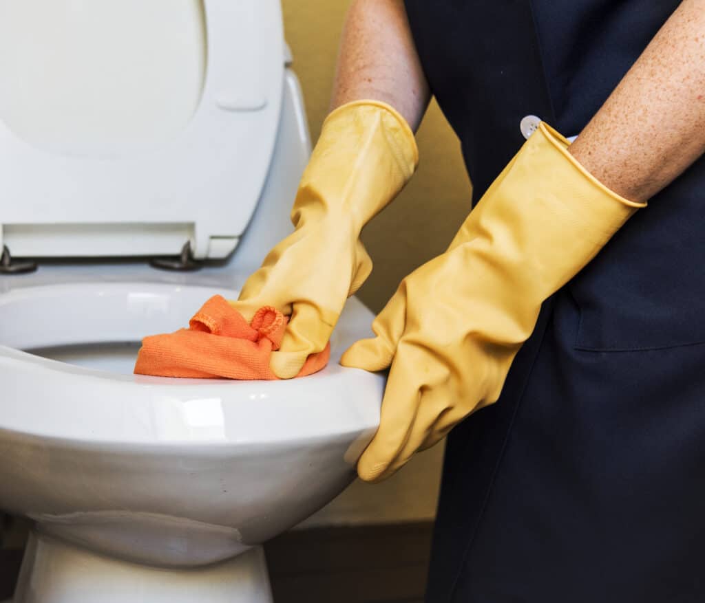 photo-of-a-cleaner-wearing-yellow-gloves-cleaning-the-toilet