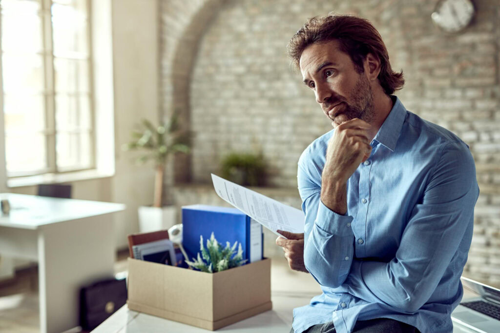 photo-of-man-sitting-on-desk-looking-into-distance-while-holding-instant-dismissal-papers-netherlands