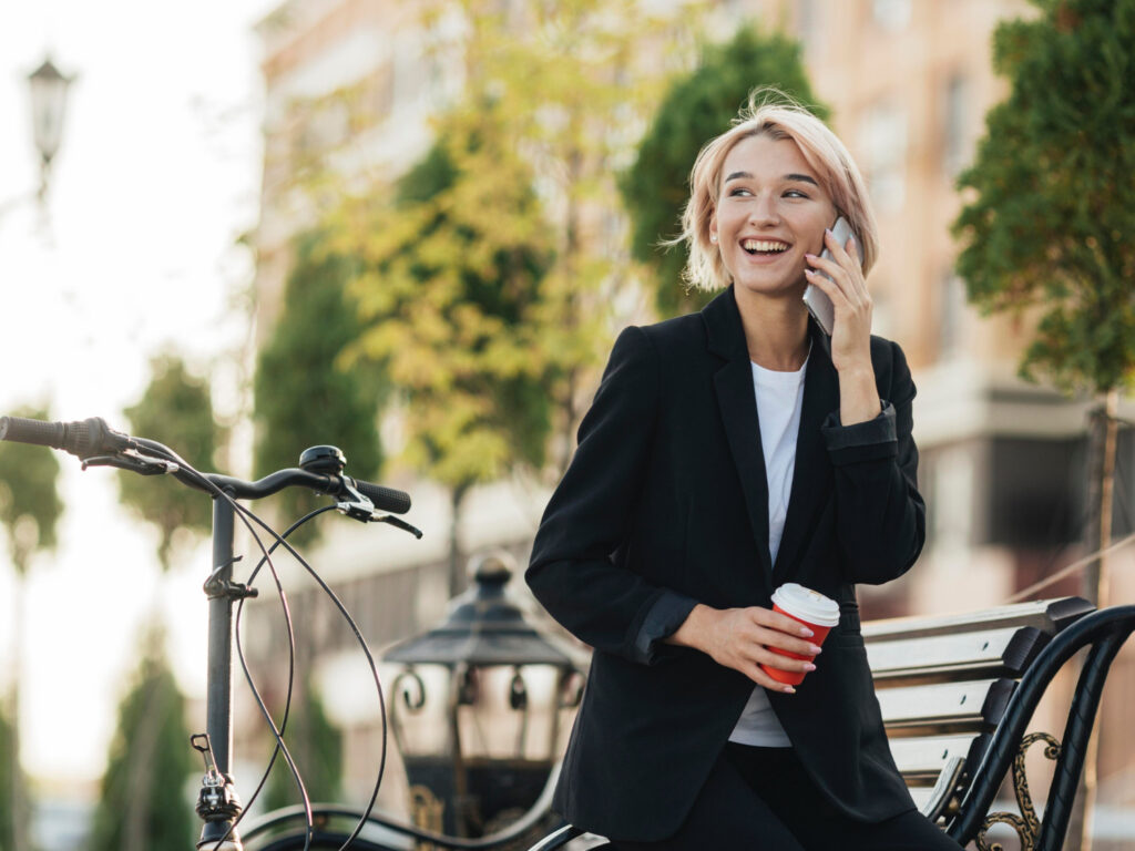 photo-of-blonde-woman-making-an-international-call-from-city-in-the-netherladns-with-tree-and-bike-behind-her