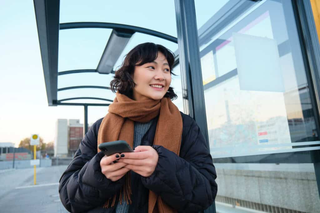 international-in-the-netherlands-holding-phone-with-dutch-esim-sim-card-as-she-waits-for-the-bus