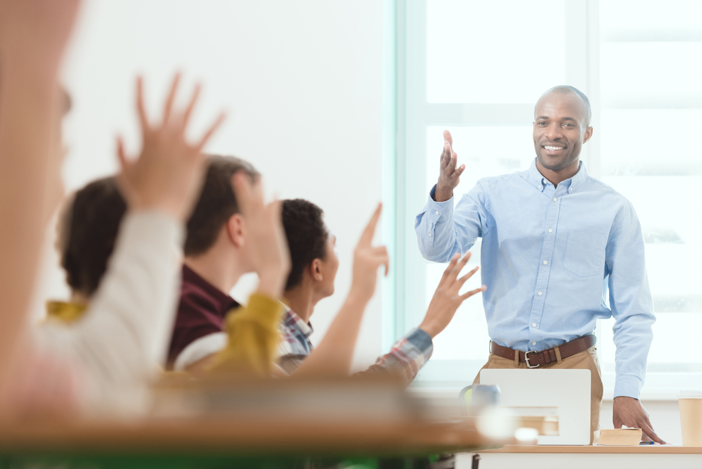 young-male-teacher-asking-questions-to-eager-international-students