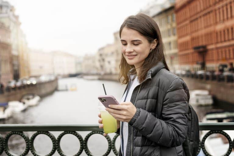 international-surfs-the-web-on-her-mobile-phone-as-she-walks-across-a-dutch-bridge