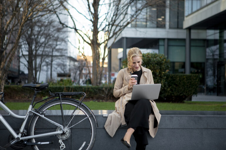 international-woman-working-in-the-netherlands-on-her-laptop-outside-drinking-coffee