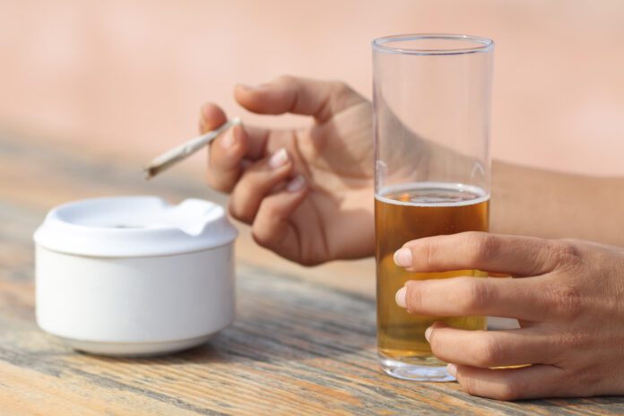 Woman hands holding a cigarette smoking and drinking alcohol in a bar in Amsterdam wondering if it's legal