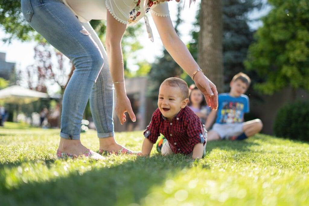 Photo-of-woman-and-children-in-garden-with-baby-crawling-on-grass
