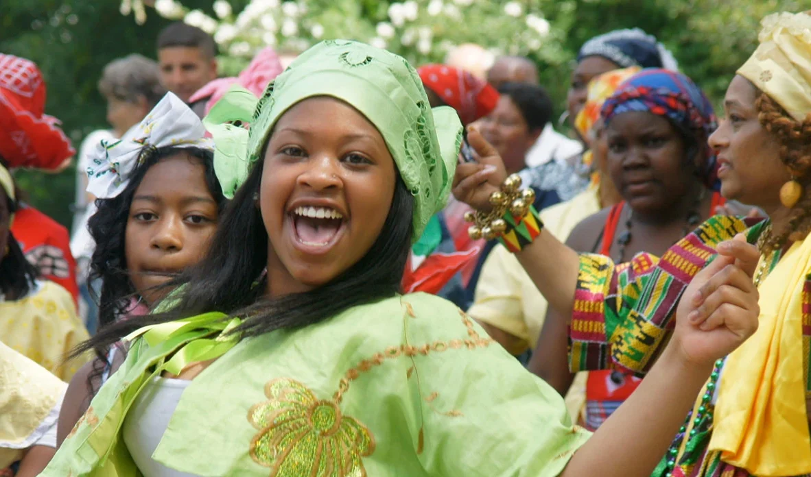 photo of dark skinned women wearing traditional clothes celebrating freedom with other women in background
