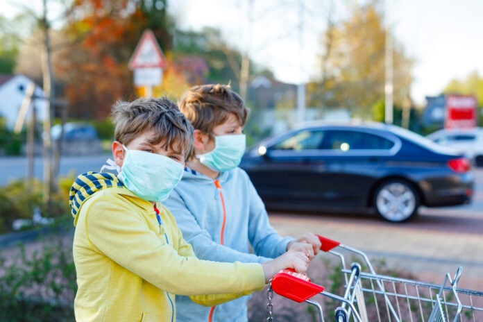 photo-of-young-boys-wearing-masks-pushing trolley-outside