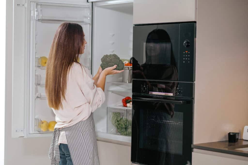photo-of-a-woman-opening-the-fridge-and-there-is-also-an-oven