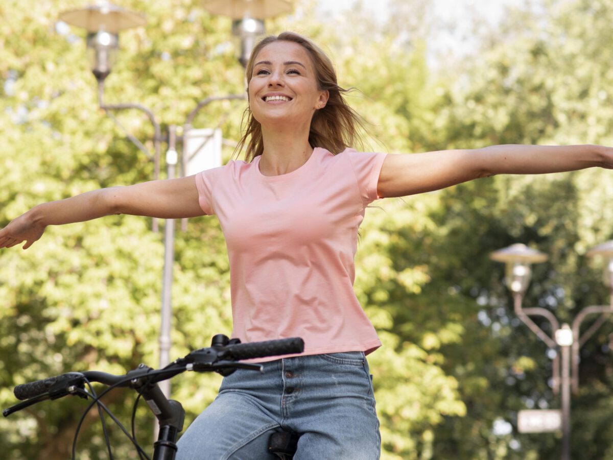 low-view-woman-smiling-riding-without-holding-bike-with-hands-in-the-woods-scaled