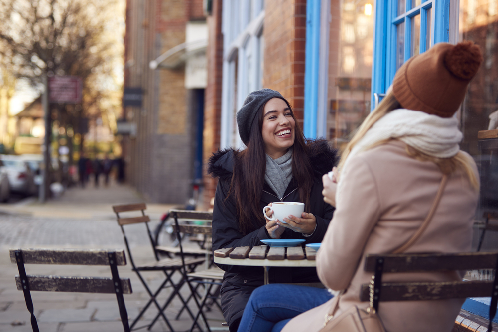 two-female-friends-hanging-out-drinking-coffee-at-dutch-terrace