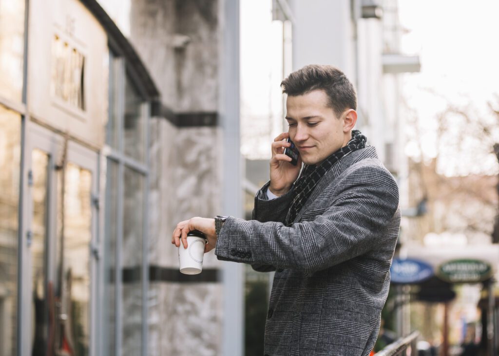 man-checking-watch-and-calling-someone-while-waiting