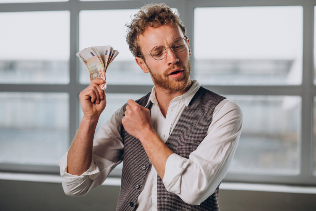 man-holding-euros-in-studio-looking-happy