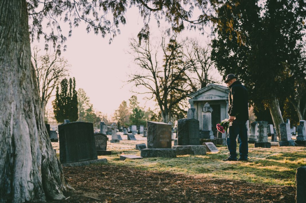 man-standing-in-cemetery-at-grave-after-death