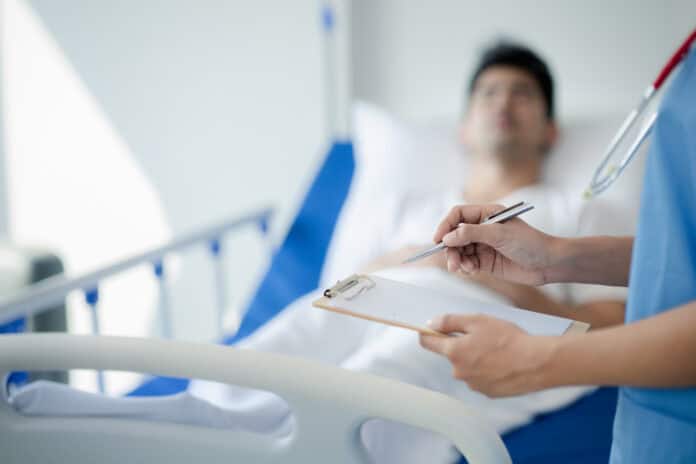 man-in-hospital-bed-medical-doctor-checking-on-him-writing