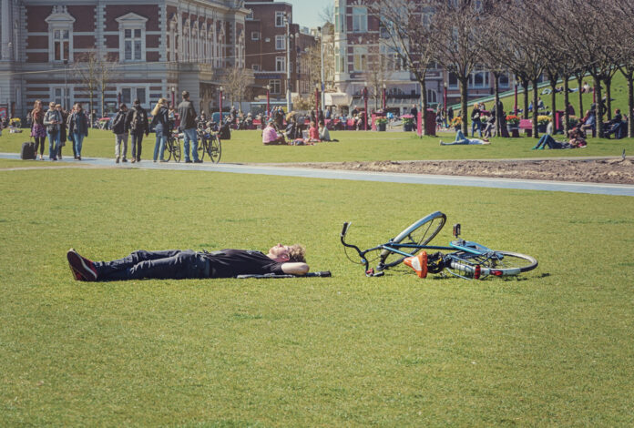 man-laying-in-park-with-bike