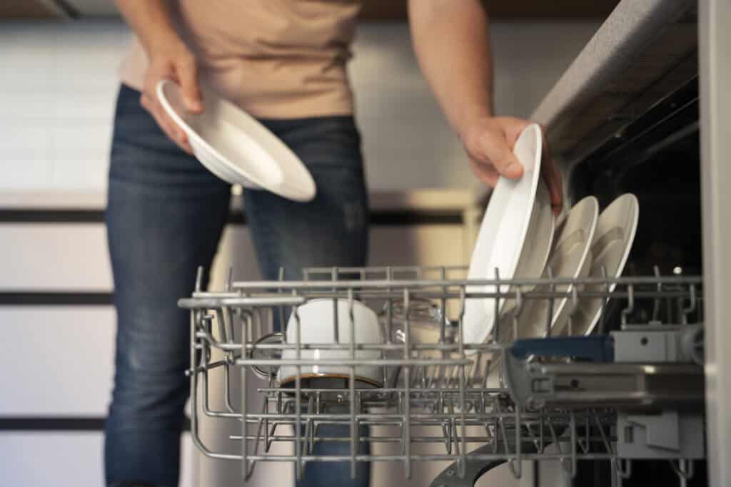 photo-of-man-loading-dishwasher-doing-chores-around-house