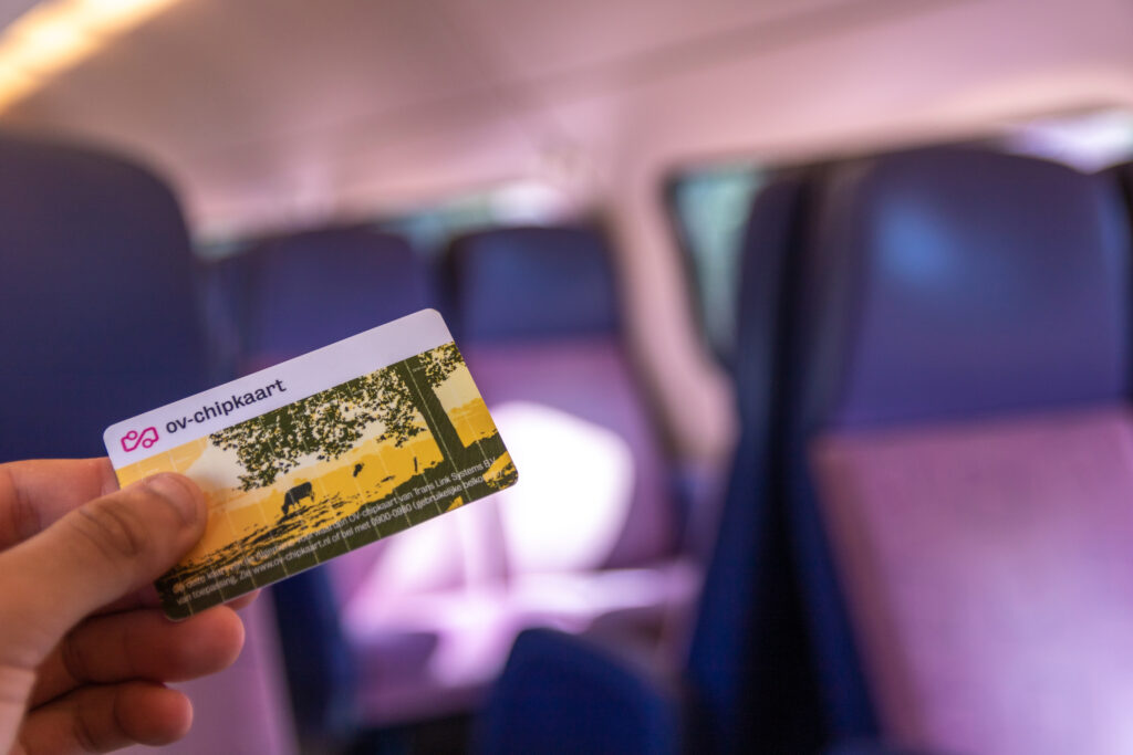 man-on-dutch-NS-train-holding-an-ov-chipcard-with-a-subscription-to-save-money-in-the-netherlands-chipkaart