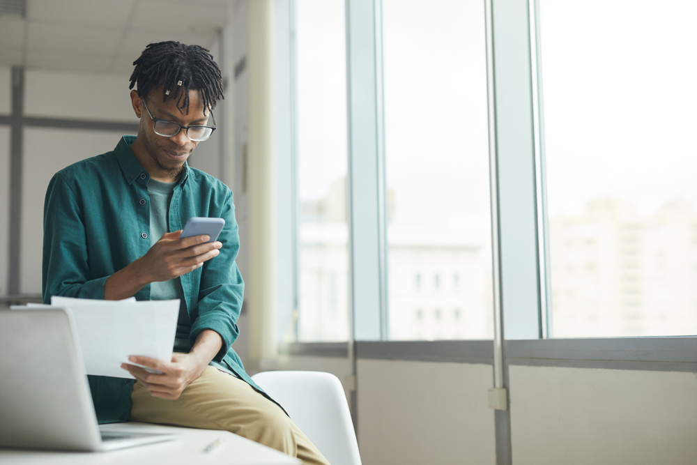 photo-young-man-reading-energy-contract-and-checking-phone