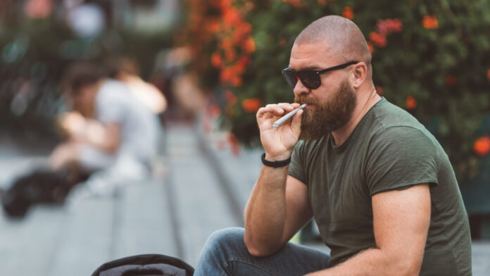 photo-of-man-sitting-in-park-in-amsterdam-smoking-joint