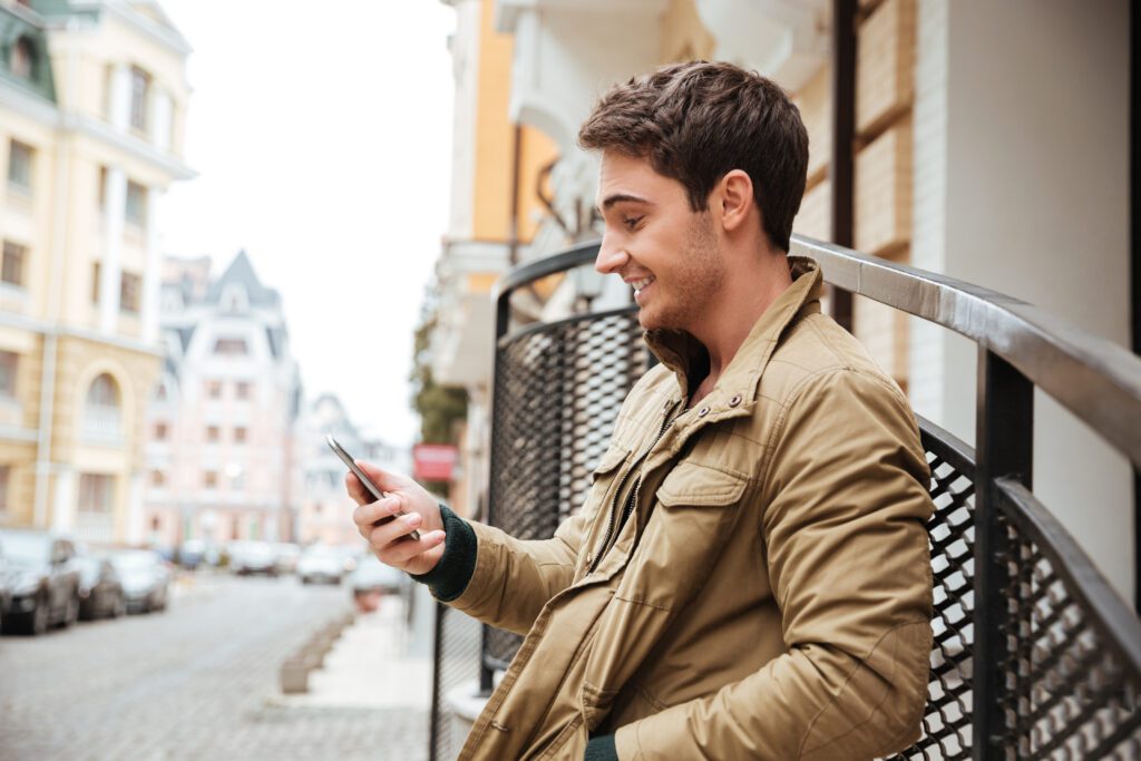 man-walking-down-a-street-in-europe-and-looking-at-his-phone-equipped-with-esim