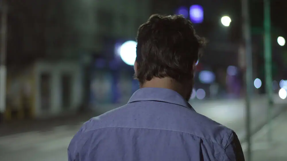 photo-of-man-walking-down-road-at-night