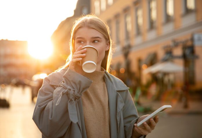 photo-of-woman-walking-in-dutch-city-drinking-coffee-with-sun-behind-her