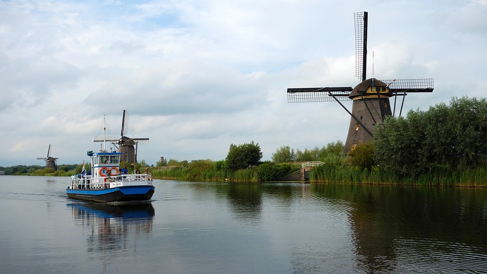 Photo-of-windmills-at-kinderdijk-with-boat-driving-past-on-the-river