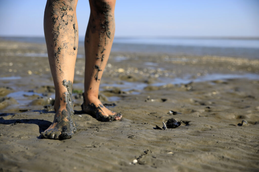 Close-up of a young woman walking across the mudflats of the Waddensea at low tide, in the Netherlands
