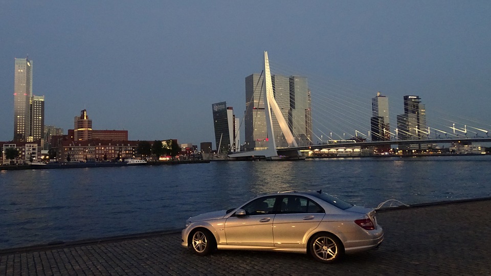 Image-of-a-silver-car-next-to-the-maas-river-in-rotterdam-with-erasmus-bridge-in-the-background