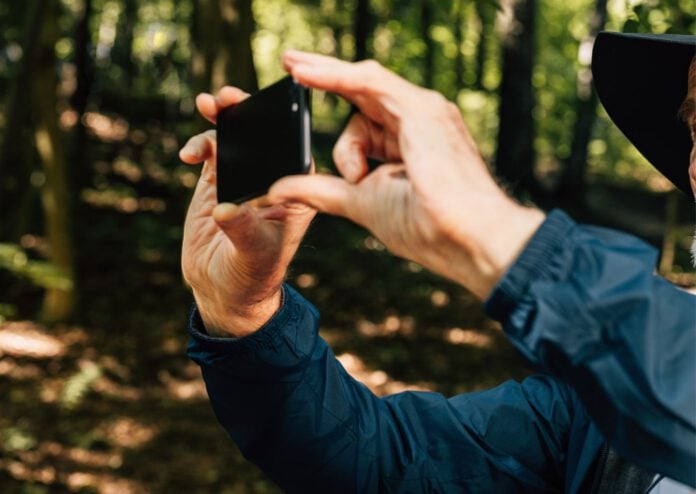 photo-of-old-mans-hands-holding-phone-recording-in-woods