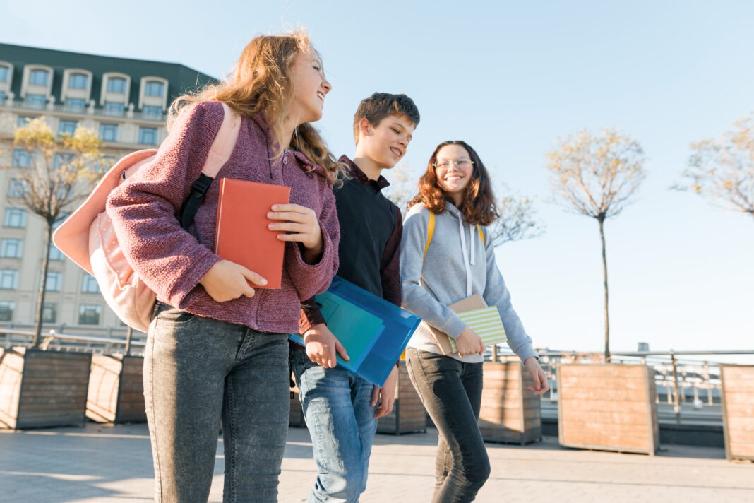 photo-of-three-young-students-in-the-netherlands-walking-with-backpacks-smiling-talking