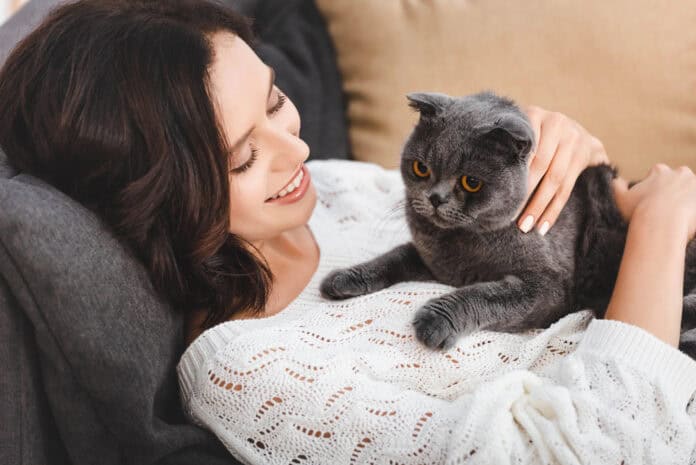 girl-lying-down-black-cat-on-lap-white-sweater-smiling-laughing