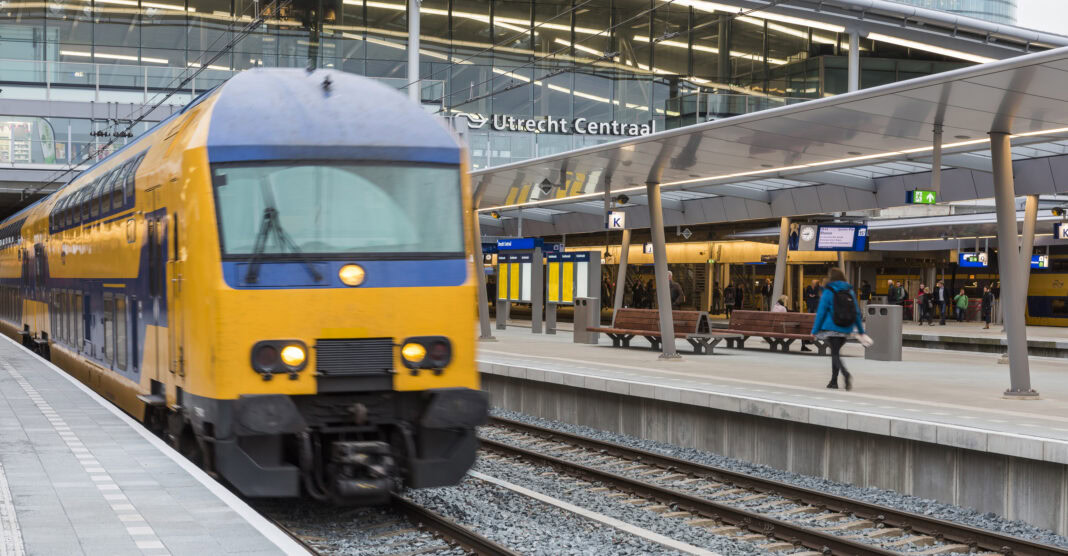 people-catching-train-at-utrecht-centraal-train-station-with-blue-yellow-ns-train-in-the-foreground