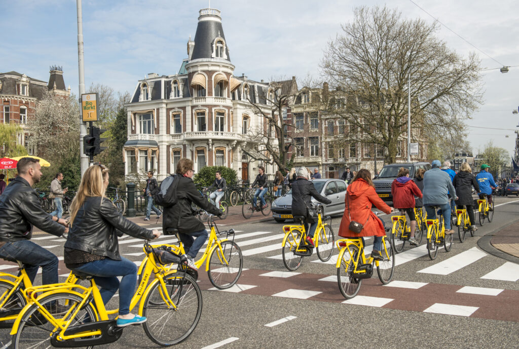 people-cycling-in-amsterdam-using-great-biking-infrastructure-showing-pros-of-moving-to-the-netherlands